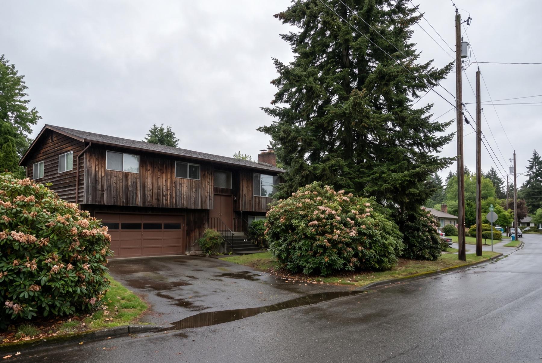 A 1970s split-level house with cedar siding on a wet Lakewood street